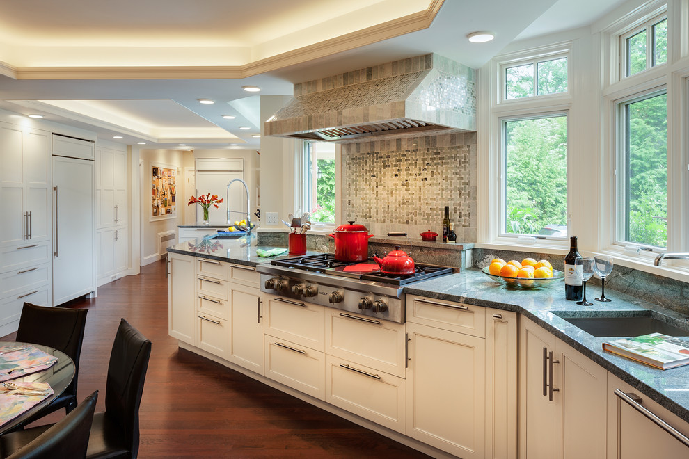 Inspiration for a large transitional galley medium tone wood floor open concept kitchen remodel in Boston with an undermount sink, shaker cabinets, white cabinets, granite countertops, multicolored backsplash, stone slab backsplash, stainless steel appliances and a peninsula