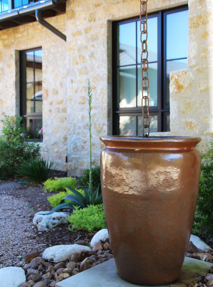 This is an example of a large mediterranean backyard full sun xeriscape for summer in Austin with gravel.