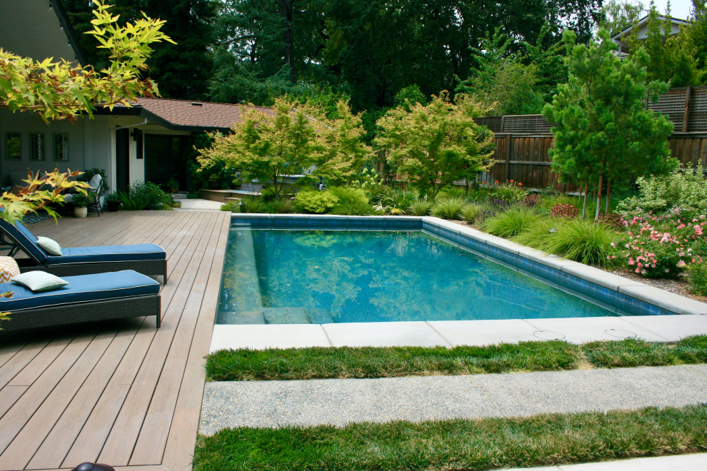 На фото: спортивный, прямоугольный ландшафтный бассейн на заднем дворе в стиле ретро с настилом