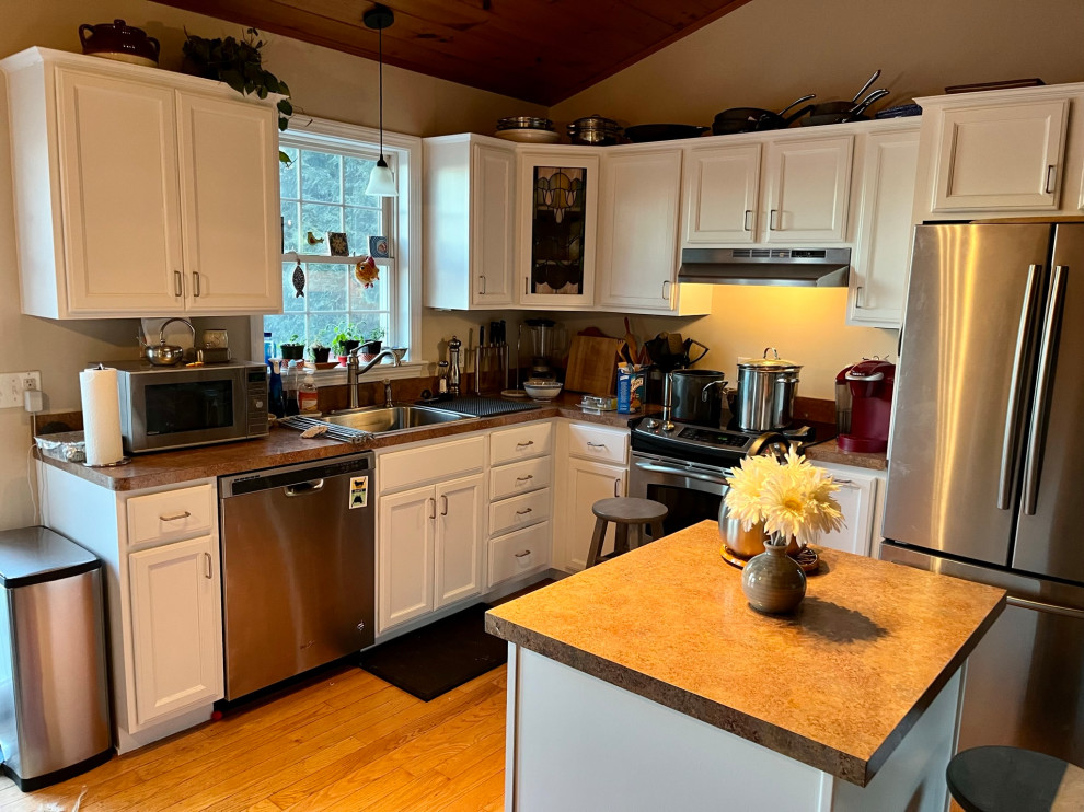 This is an example of a mid-sized modern l-shaped eat-in kitchen in Boston with a drop-in sink, beaded inset cabinets, white cabinets, wood benchtops, stainless steel appliances, medium hardwood floors, with island and wood.