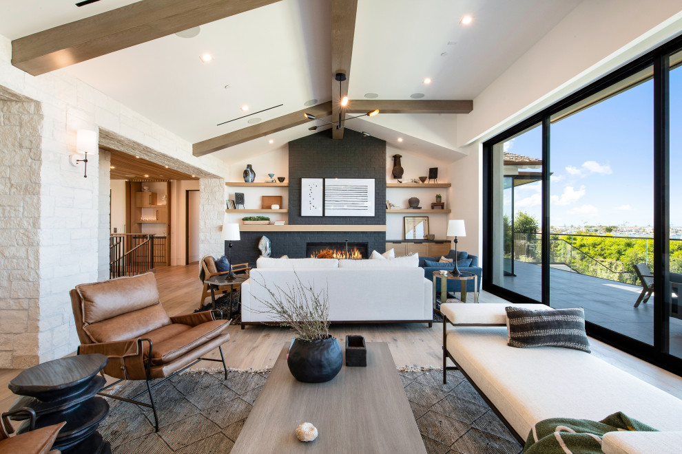 Beach style open concept living room in Orange County with white walls, light hardwood floors, a standard fireplace, a brick fireplace surround, no tv, exposed beam and brick walls.