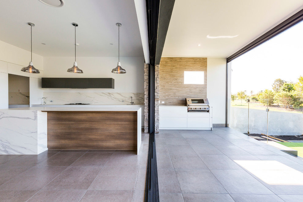 This is an example of a mid-sized contemporary backyard verandah in Gold Coast - Tweed with an outdoor kitchen, tile and a roof extension.