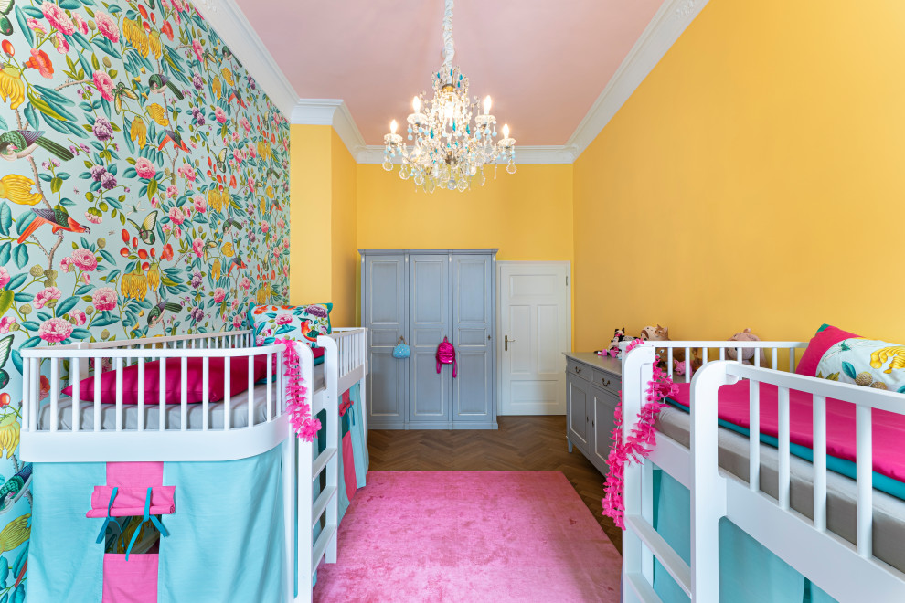 This is an example of a mid-sized eclectic gender-neutral kids' room for kids 4-10 years old in Munich with yellow walls, medium hardwood floors, brown floor and wallpaper.