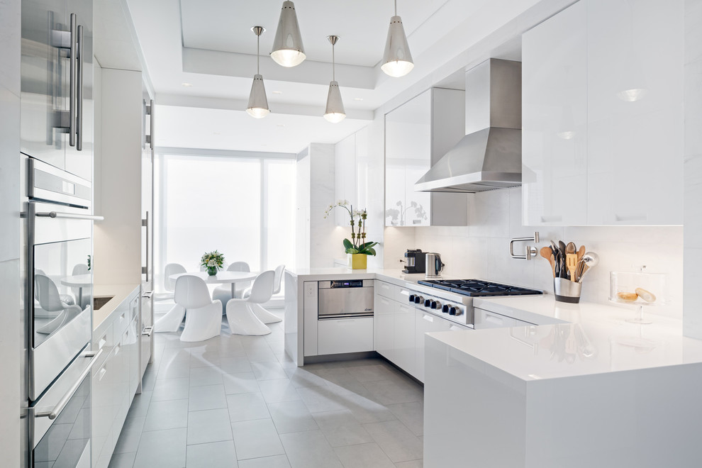 This is an example of a contemporary eat-in kitchen in New York with white cabinets, stainless steel appliances and slate floors.
