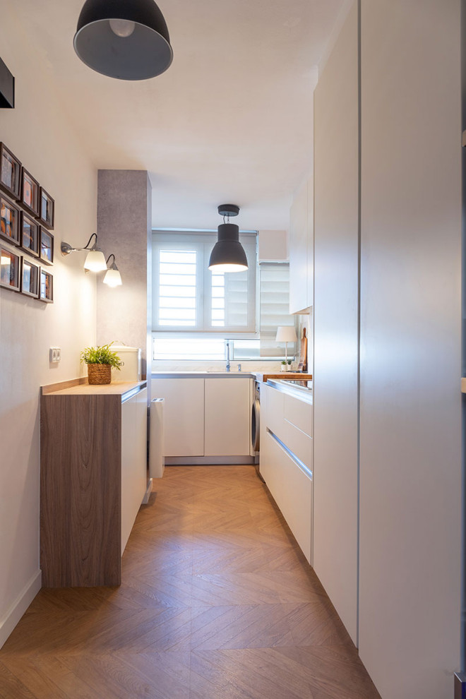 Kleine Moderne Küche mit flächenbündigen Schrankfronten, weißen Schränken, Arbeitsplatte aus Holz, Küchengeräten aus Edelstahl und beiger Arbeitsplatte in Sonstige