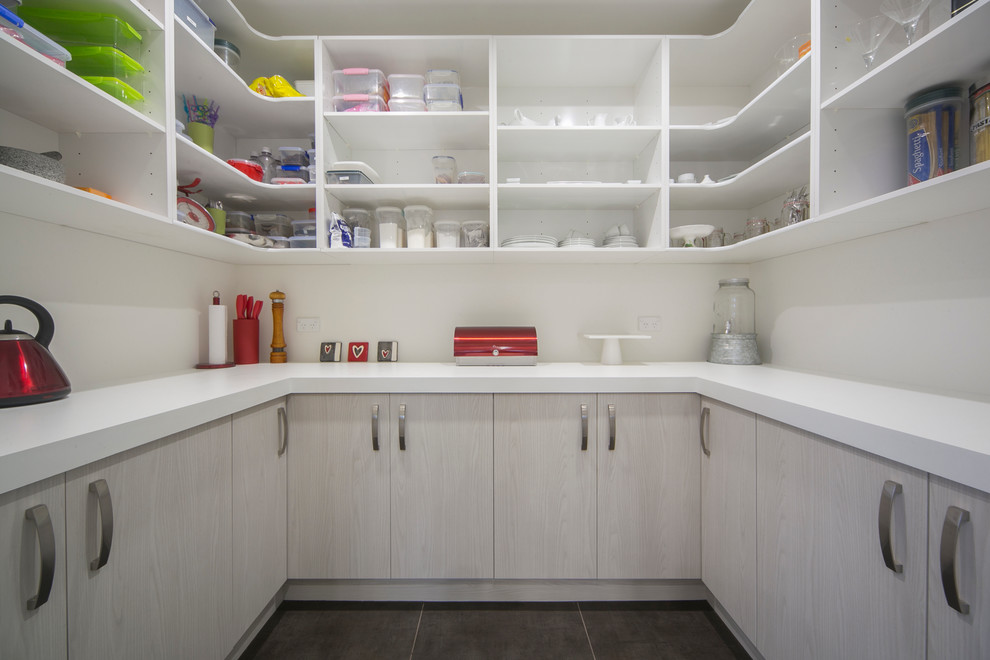 Mid-sized modern single-wall kitchen pantry in Auckland with an undermount sink, flat-panel cabinets, white cabinets, quartz benchtops, white splashback, glass sheet splashback, stainless steel appliances, ceramic floors and with island.