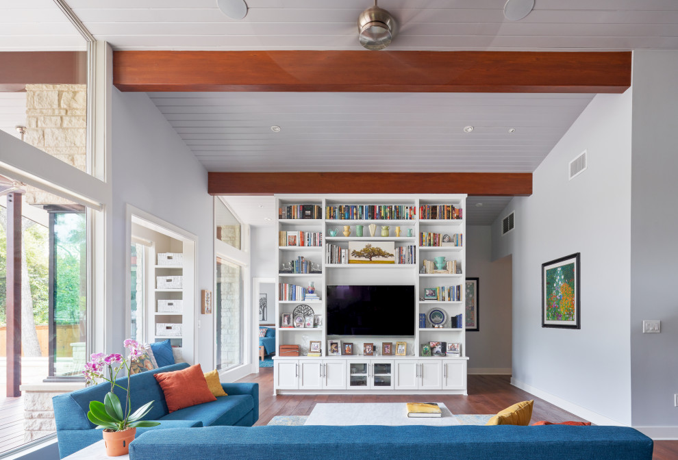 Foto på ett mellanstort 50 tals allrum med öppen planlösning, med ett bibliotek, grå väggar, mellanmörkt trägolv, en inbyggd mediavägg och brunt golv