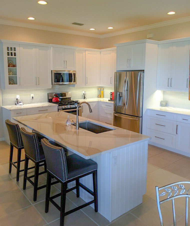 Photo of a mid-sized transitional l-shaped eat-in kitchen in Tampa with an undermount sink, flat-panel cabinets, white cabinets, quartz benchtops, white splashback, ceramic splashback, stainless steel appliances, porcelain floors, with island, beige floor and white benchtop.