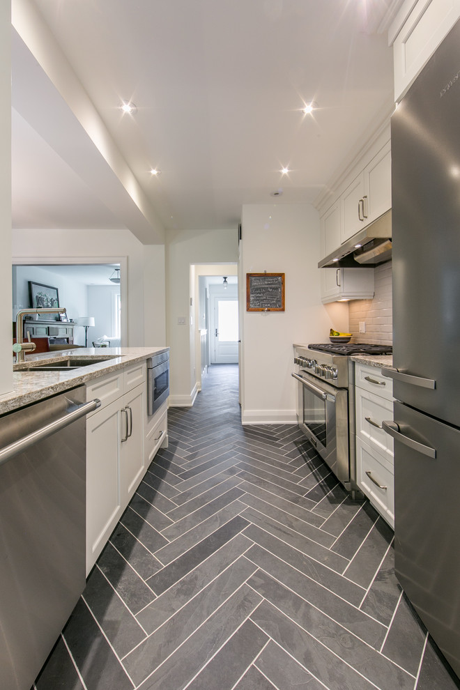 Example of a mid-sized transitional galley slate floor eat-in kitchen design in Toronto with shaker cabinets, white cabinets, stainless steel appliances, an undermount sink, quartzite countertops, gray backsplash, a peninsula and ceramic backsplash