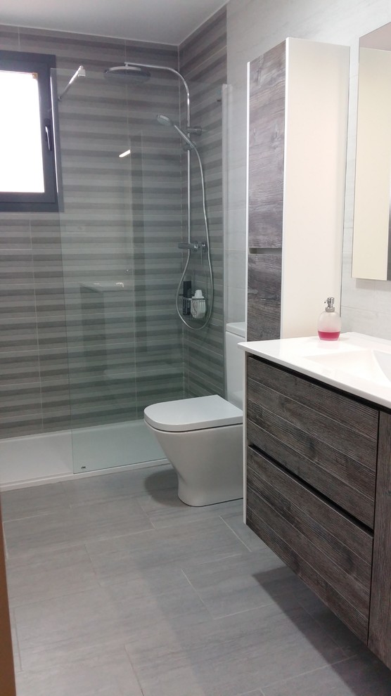 Mid-sized modern master bathroom in Barcelona with flat-panel cabinets, medium wood cabinets, a curbless shower, a one-piece toilet, multi-coloured tile, ceramic tile, multi-coloured walls, porcelain floors, an integrated sink and engineered quartz benchtops.