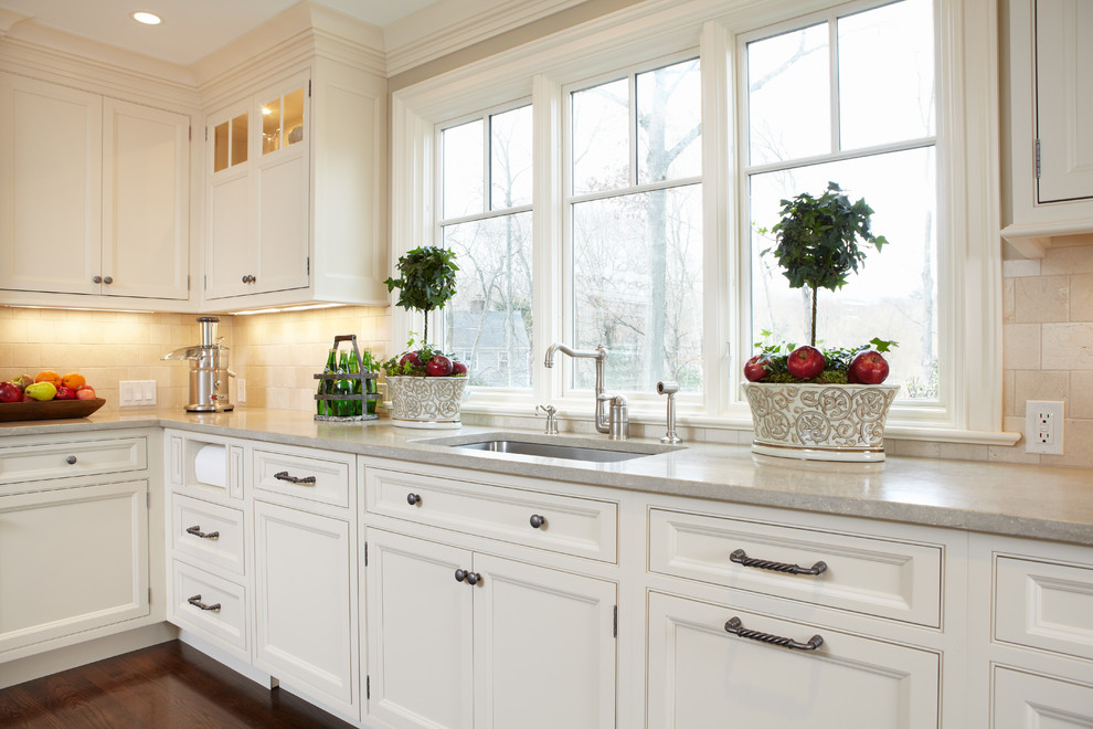 This is an example of a traditional eat-in kitchen in New York with an undermount sink, beaded inset cabinets, white cabinets, marble benchtops and beige splashback.
