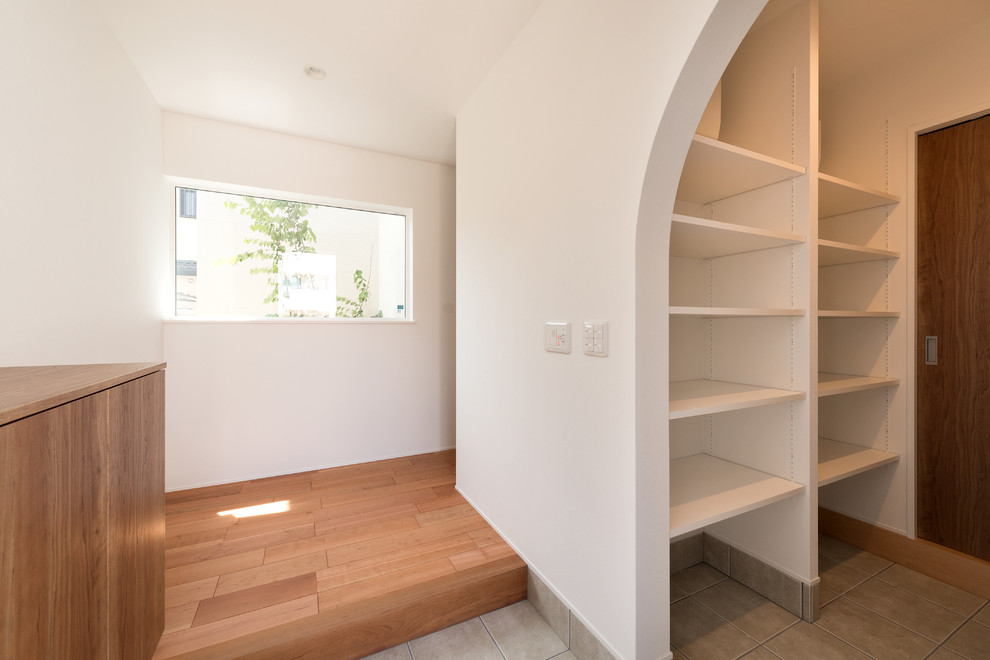 Photo of a modern entryway in Kyoto with white walls and medium hardwood floors.
