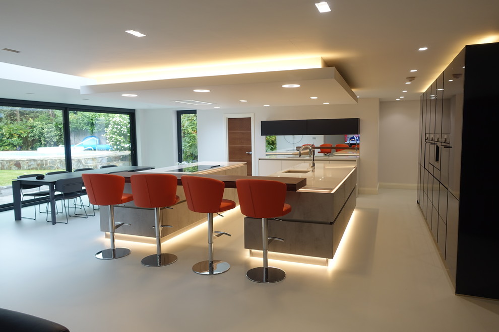 Photo of an expansive modern galley open plan kitchen in Surrey with an integrated sink, flat-panel cabinets, grey cabinets, granite benchtops, panelled appliances, multiple islands, white floor and white benchtop.