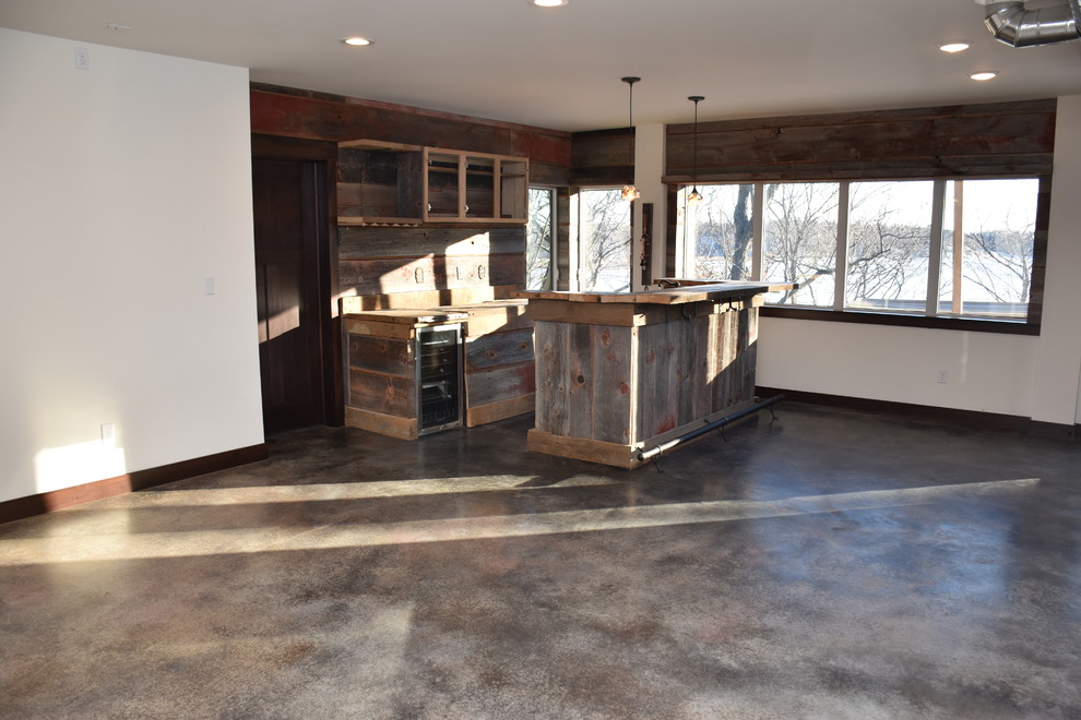 Design ideas for a mid-sized country galley seated home bar in Milwaukee with flat-panel cabinets, medium wood cabinets, wood benchtops, brown splashback, timber splashback, concrete floors and brown floor.