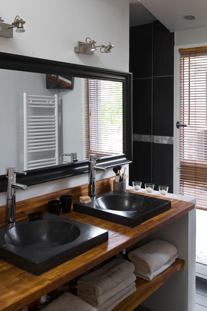 Mid-sized contemporary bathroom in Paris with a drop-in sink, wood benchtops, white walls, open cabinets, medium wood cabinets, gray tile and black tile.