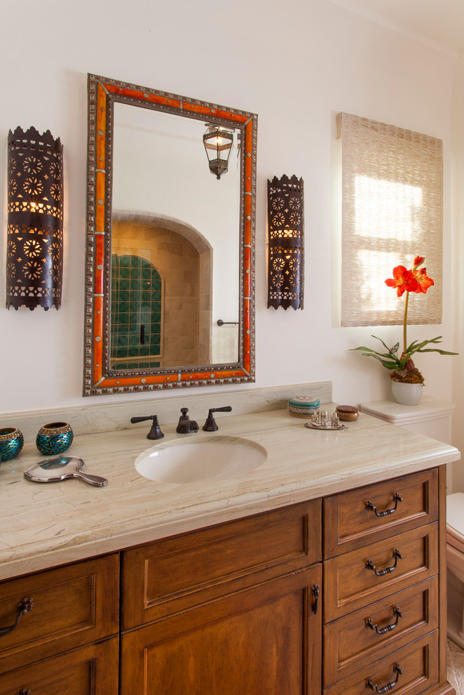 Inspiration for a small mediterranean 3/4 bathroom in San Diego with beaded inset cabinets, medium wood cabinets, a two-piece toilet, white walls, travertine floors, an undermount sink and engineered quartz benchtops.