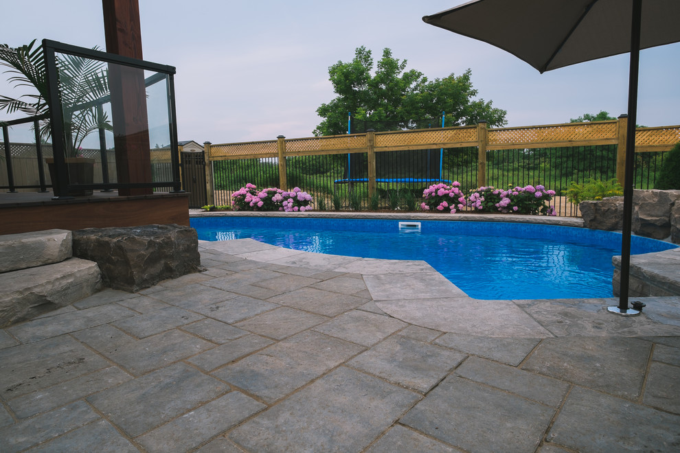 This is an example of a mid-sized modern backyard kidney-shaped pool in Toronto with concrete pavers.