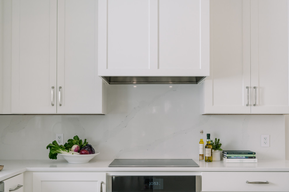 Example of a large transitional l-shaped laminate floor and brown floor eat-in kitchen design with an undermount sink, shaker cabinets, white cabinets, quartz countertops, white backsplash, quartz backsplash, stainless steel appliances, an island and white countertops