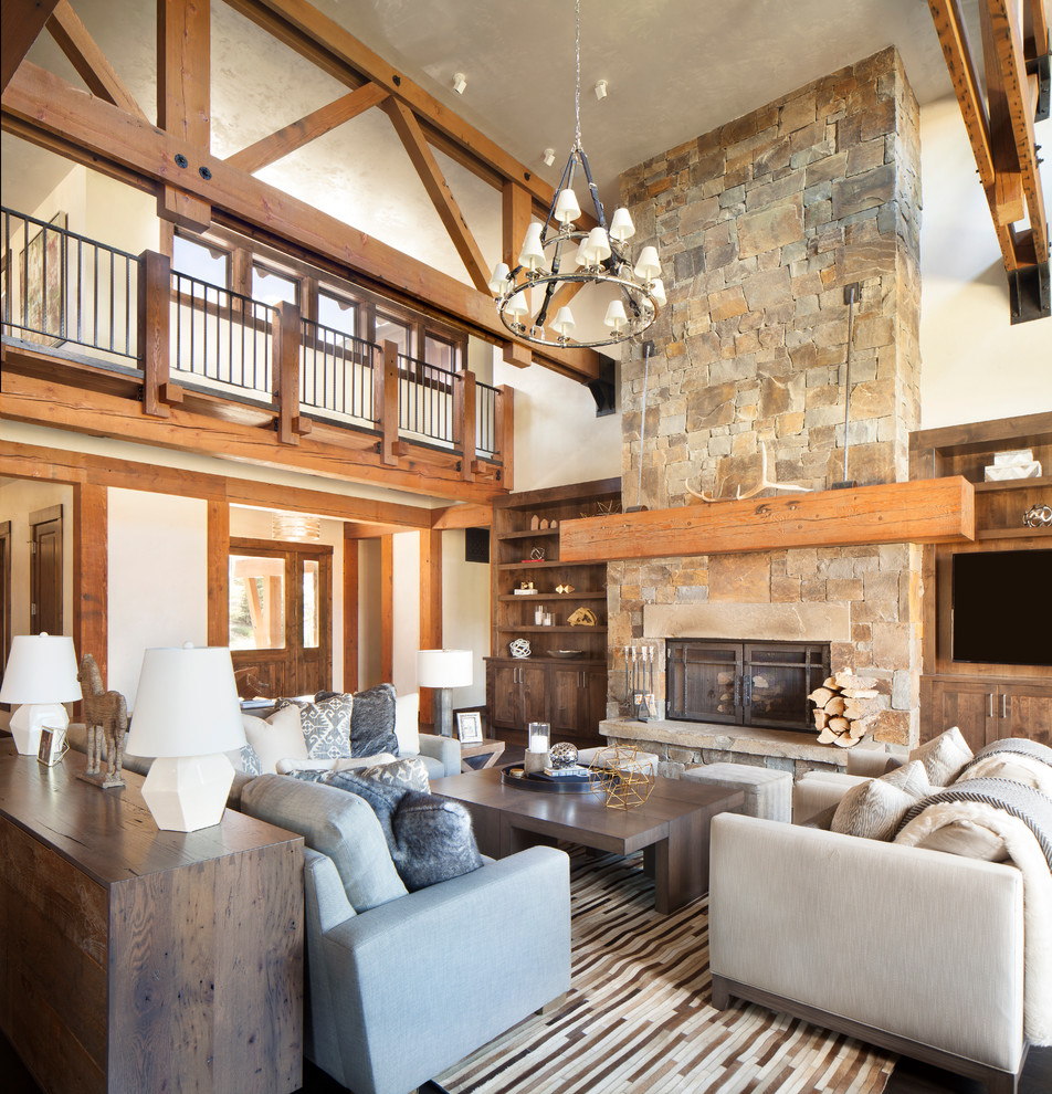 This is an example of a large country formal enclosed living room in Other with beige walls, dark hardwood floors, a standard fireplace, a stone fireplace surround, a built-in media wall and brown floor.