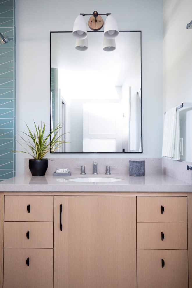Medium sized contemporary family bathroom in San Francisco with flat-panel cabinets, light wood cabinets, an alcove bath, a shower/bath combination, blue tiles, ceramic tiles, white walls, terrazzo flooring, a submerged sink, engineered stone worktops, grey floors, a shower curtain, beige worktops, an enclosed toilet, a single sink and a freestanding vanity unit.