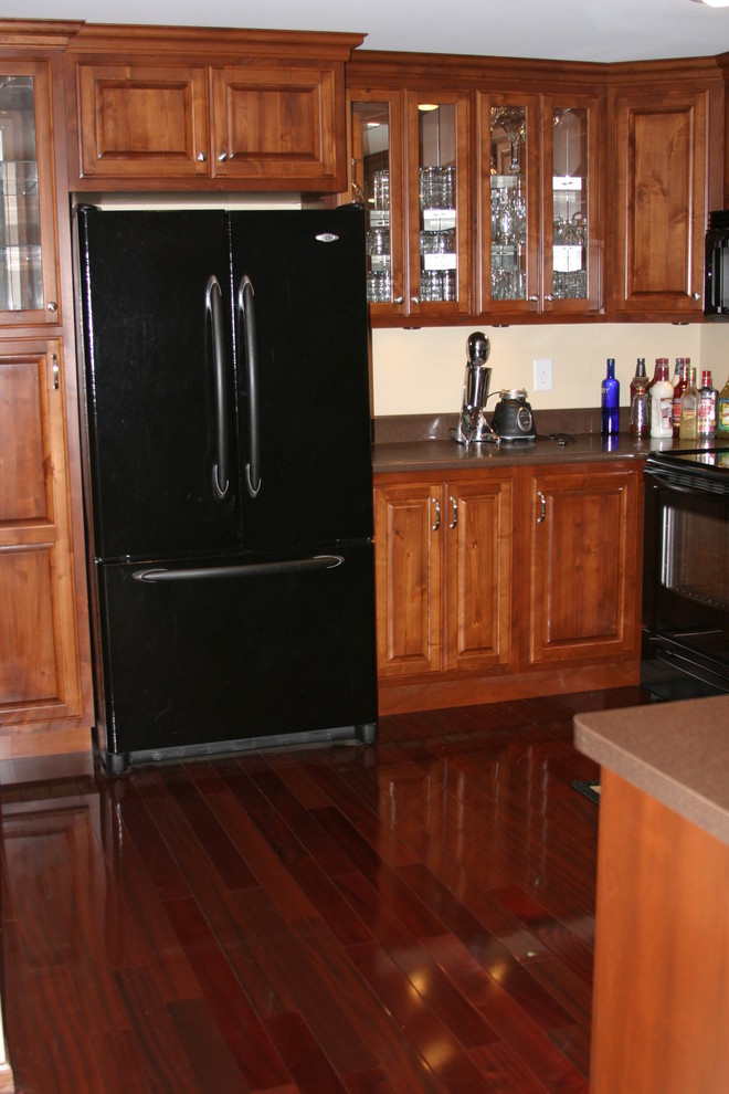 Example of a small u-shaped open concept kitchen design with raised-panel cabinets, dark wood cabinets, black appliances and a peninsula