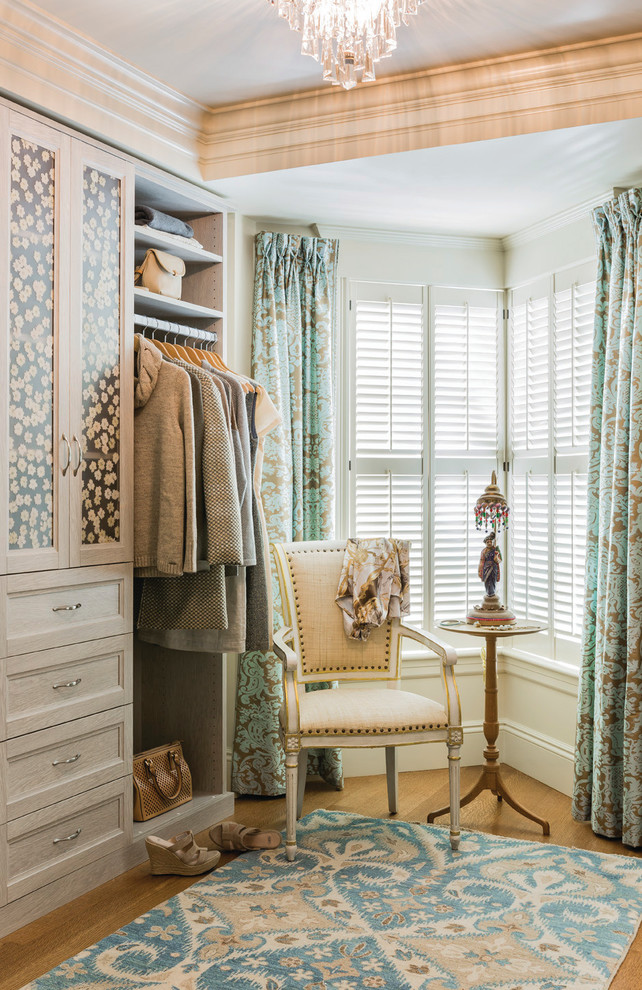 Photo of a large transitional gender-neutral walk-in wardrobe in Boston with medium hardwood floors, recessed-panel cabinets and beige cabinets.