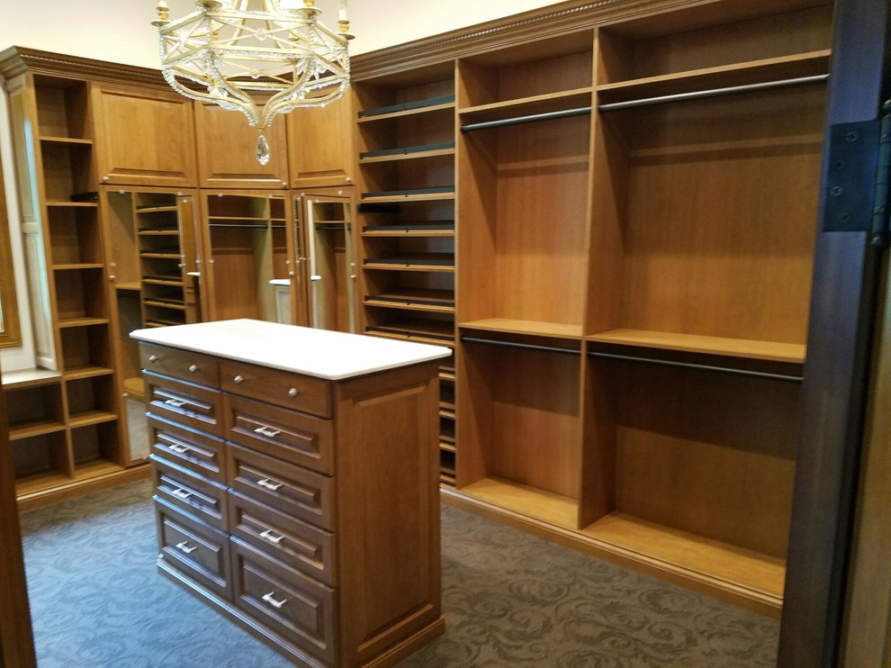 Photo of a large traditional gender-neutral dressing room in Indianapolis with raised-panel cabinets, medium wood cabinets and carpet.