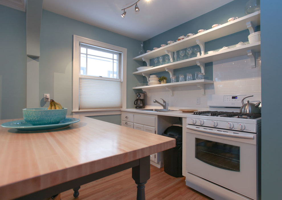 Eat-in kitchen - small transitional single-wall light wood floor eat-in kitchen idea in Minneapolis with a single-bowl sink, open cabinets, white cabinets, laminate countertops, white backsplash, subway tile backsplash, white appliances and an island