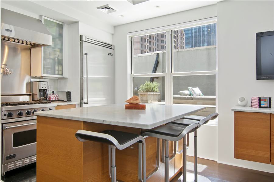 This is an example of a small modern l-shaped kitchen in New York with flat-panel cabinets, medium wood cabinets, marble benchtops, metallic splashback and with island.