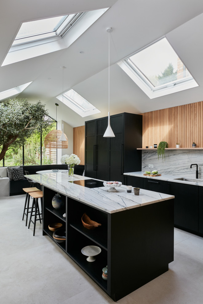 Large scandinavian open plan kitchen in London with a drop-in sink, flat-panel cabinets, black cabinets, quartzite benchtops, multi-coloured splashback, black appliances, with island and multi-coloured benchtop.
