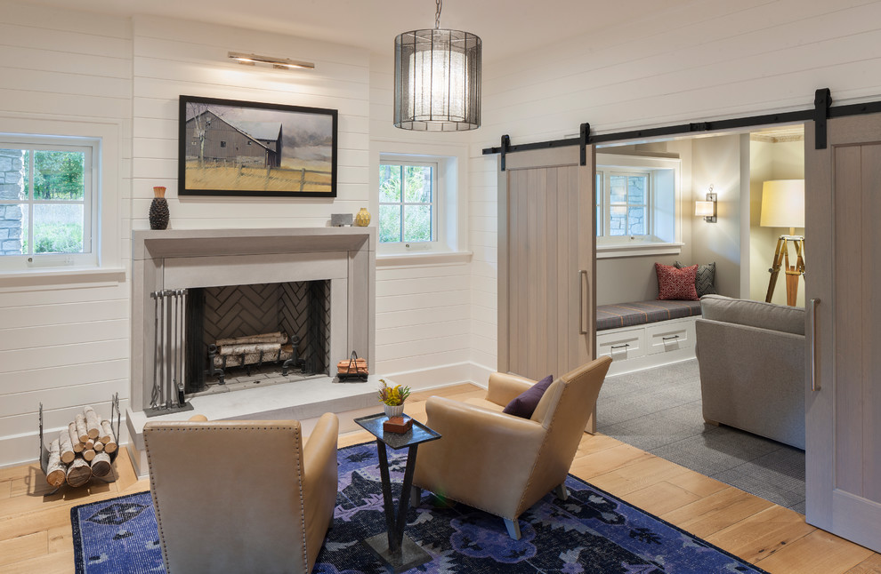 This is an example of a country look-out basement in Grand Rapids with white walls, light hardwood floors and a standard fireplace.