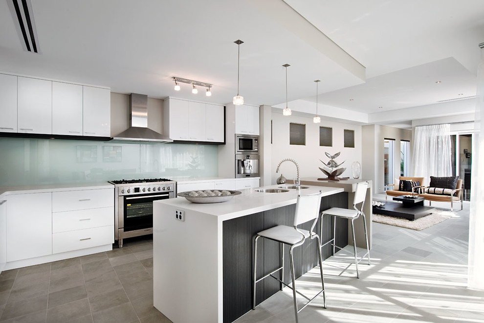 This is an example of a contemporary open plan kitchen in Perth with a double-bowl sink, flat-panel cabinets, white cabinets, glass sheet splashback, stainless steel appliances and white splashback.