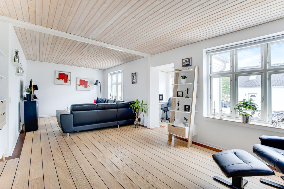This is an example of a large scandinavian open concept living room in Aalborg with white walls, light hardwood floors and beige floor.
