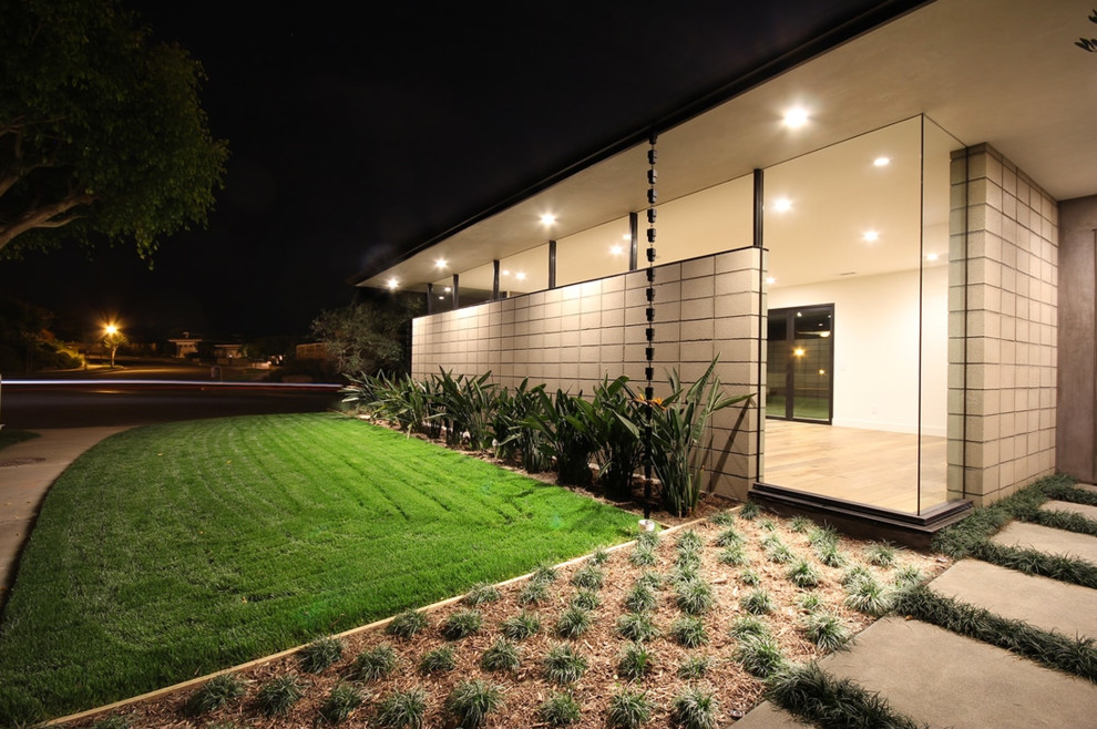 Midcentury one-storey concrete grey house exterior in Los Angeles with a hip roof and a metal roof.