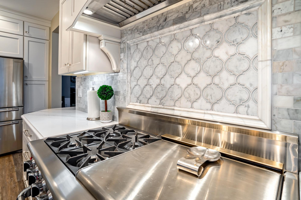 Eat-in kitchen - large transitional single-wall medium tone wood floor and brown floor eat-in kitchen idea in Philadelphia with a farmhouse sink, shaker cabinets, white cabinets, quartz countertops, gray backsplash, porcelain backsplash, stainless steel appliances, an island and white countertops