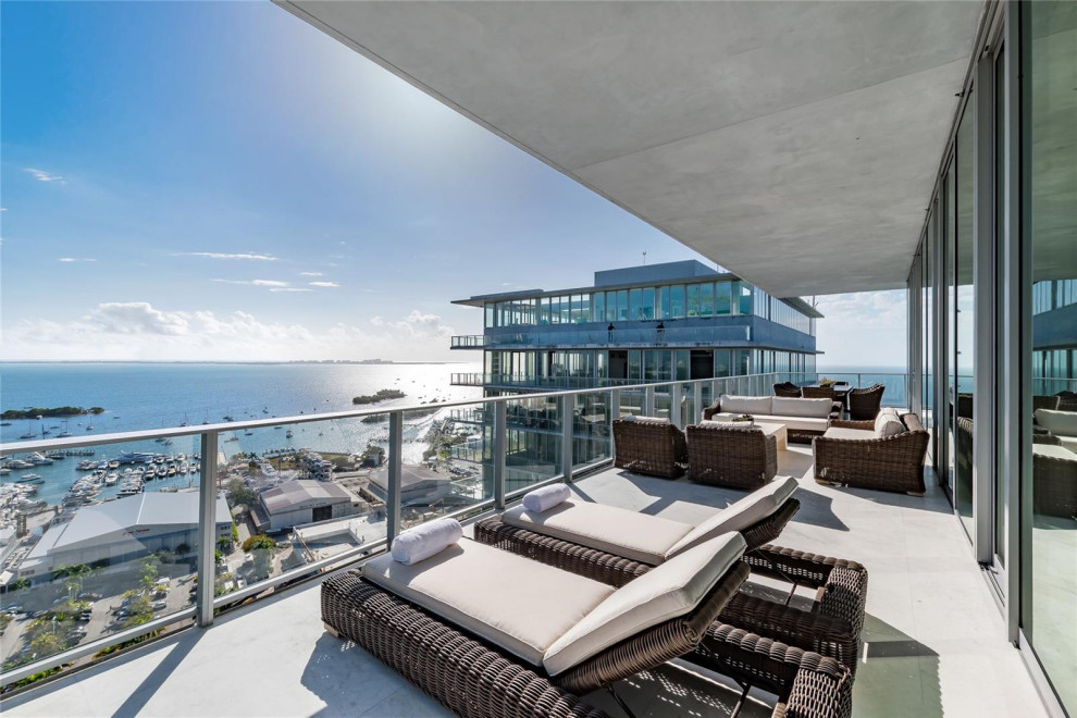 Design ideas for a large contemporary balcony in Miami with an awning and glass railing.