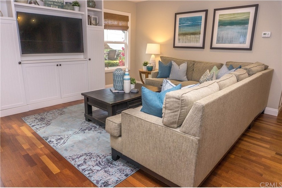 Inspiration for a mid-sized beach style open concept family room in Orange County with beige walls, medium hardwood floors, a built-in media wall, brown floor and no fireplace.