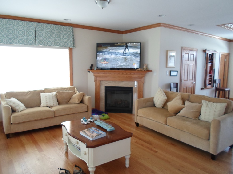 Photo of a mid-sized beach style open concept living room in New York with beige walls, light hardwood floors, a corner fireplace, a tile fireplace surround and a freestanding tv.