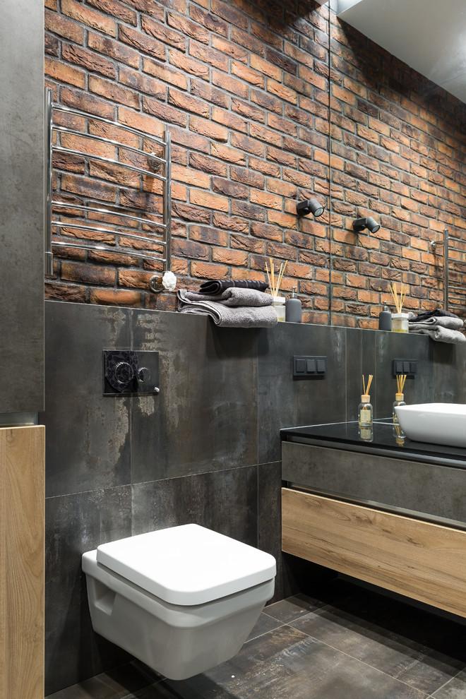 Design ideas for a mid-sized contemporary bathroom in Saint Petersburg with flat-panel cabinets, medium wood cabinets, a wall-mount toilet, black tile, porcelain tile, porcelain floors, a vessel sink, solid surface benchtops, black floor and black benchtops.