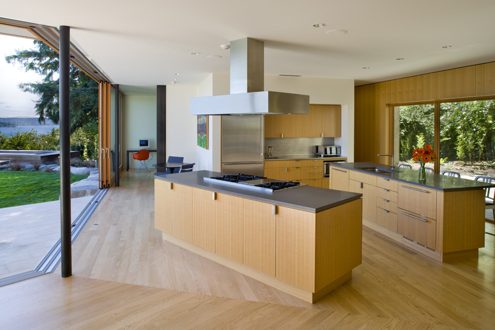 This is an example of a contemporary kitchen in Seattle with stainless steel appliances, an undermount sink, flat-panel cabinets, light wood cabinets and multiple islands.