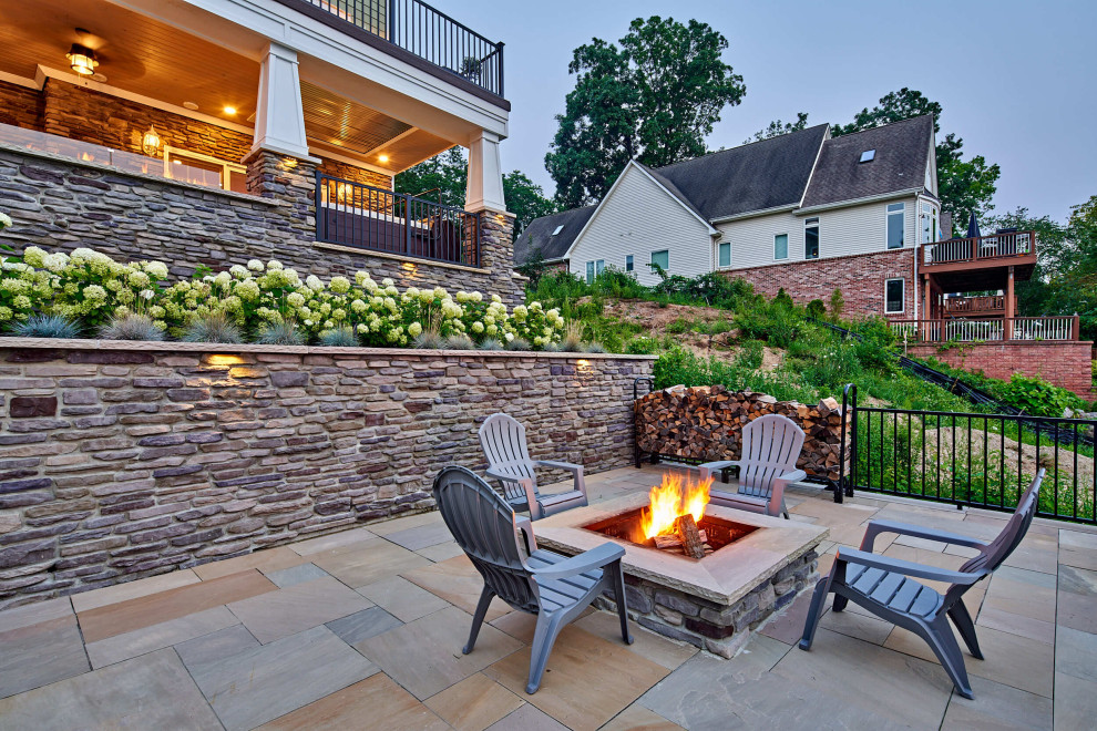 This is an example of a large traditional back patio in Detroit with a fire feature, concrete paving and an awning.