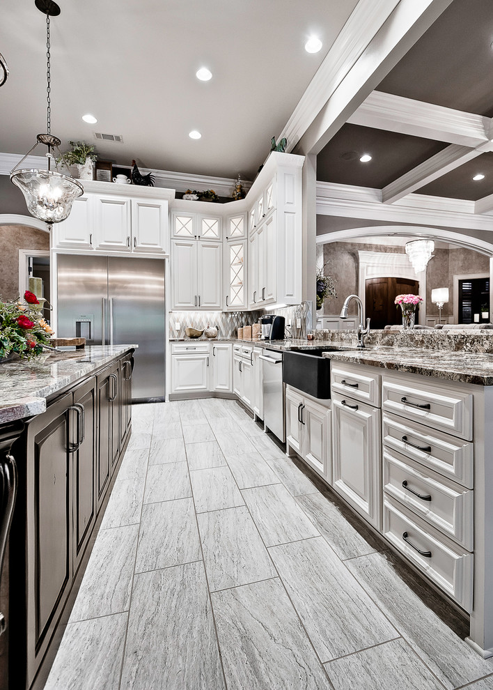 Inspiration for a large traditional u-shaped open plan kitchen in Other with a farmhouse sink, raised-panel cabinets, white cabinets, granite benchtops, brown splashback, glass tile splashback, white appliances, porcelain floors, with island, beige floor and brown benchtop.