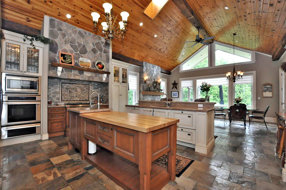 Inspiration for a mid-sized country open plan kitchen in Toronto with an undermount sink, beaded inset cabinets, medium wood cabinets, granite benchtops, grey splashback, porcelain splashback, stainless steel appliances, slate floors, multiple islands and grey floor.