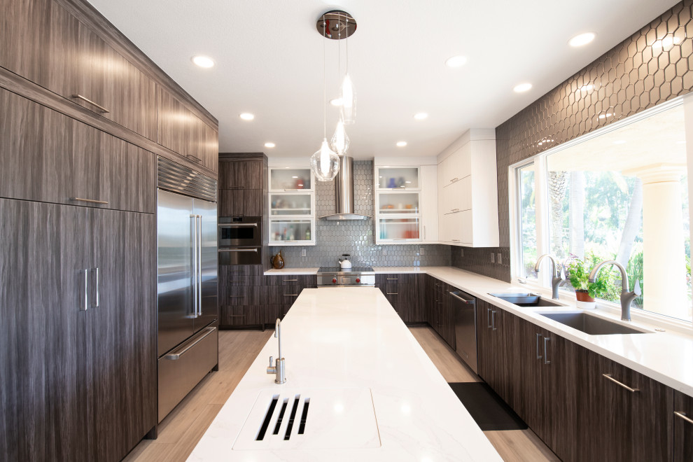 This is an example of a large contemporary u-shaped eat-in kitchen in San Diego with an undermount sink, flat-panel cabinets, grey cabinets, quartz benchtops, grey splashback, glass tile splashback, porcelain floors, with island and white benchtop.