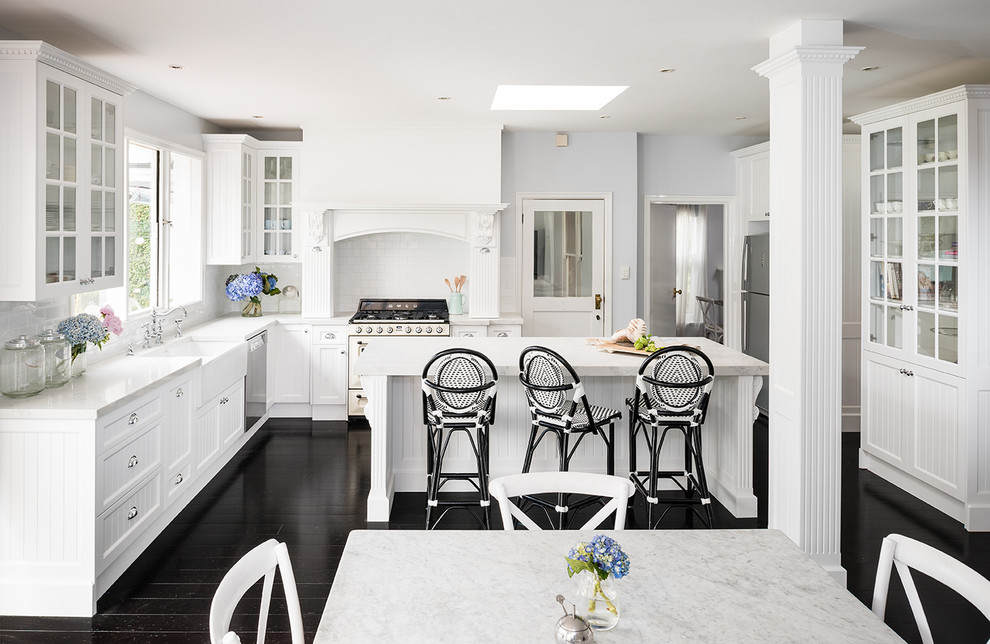 Photo of a large country kitchen in Melbourne with a farmhouse sink, recessed-panel cabinets, white cabinets, marble benchtops, dark hardwood floors and with island.