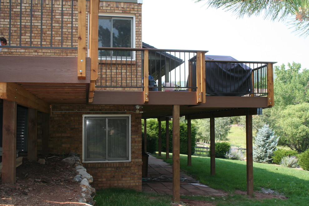 Photo of a large traditional backyard deck in Denver with a fire feature and a roof extension.