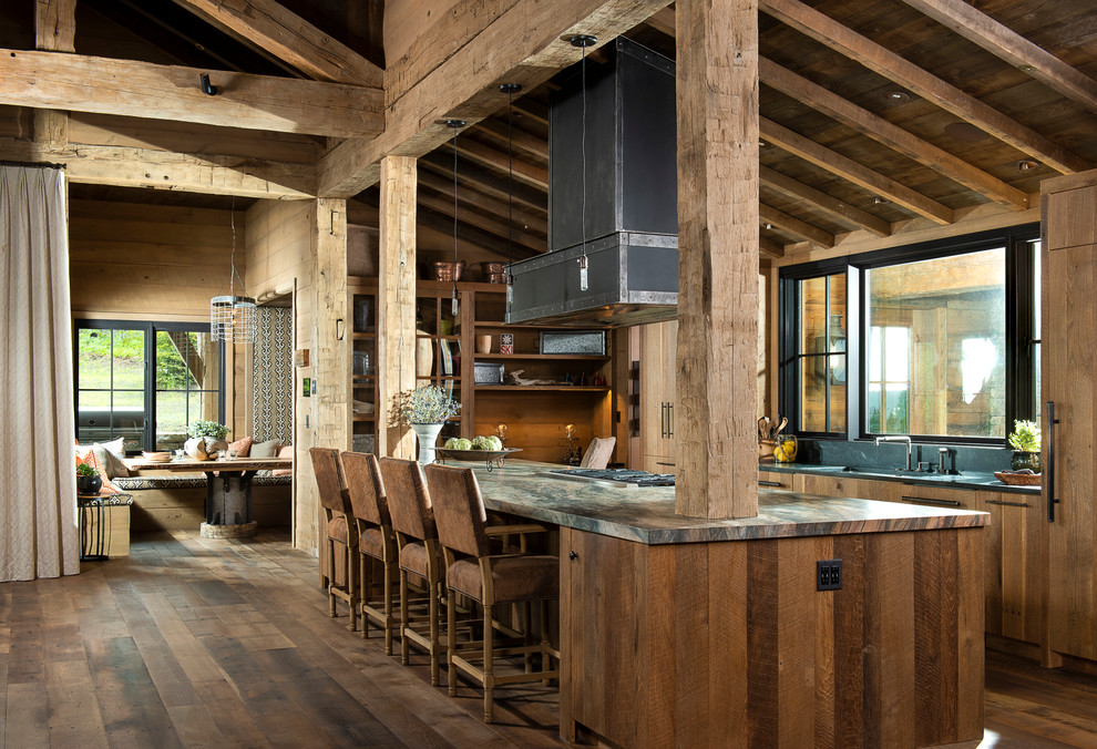 Inspiration for a large rustic galley brown floor and dark wood floor eat-in kitchen remodel with an undermount sink, flat-panel cabinets, granite countertops, black backsplash, stone slab backsplash, paneled appliances, an island, medium tone wood cabinets and gray countertops