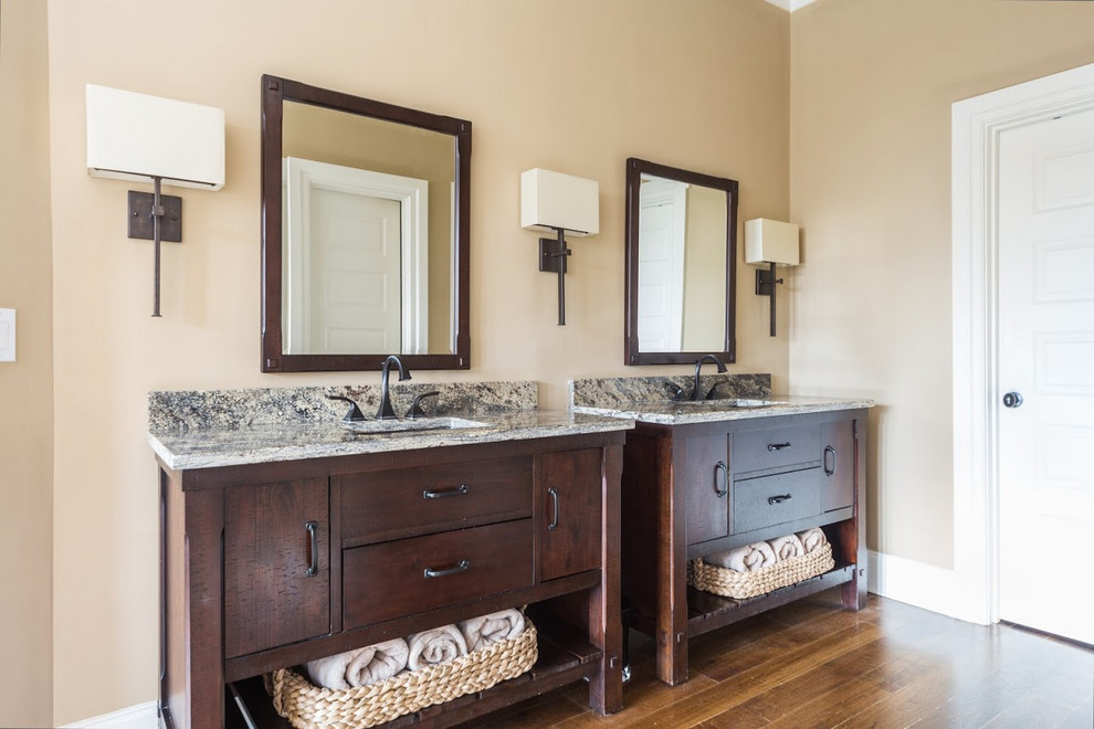 This is an example of a large traditional master bathroom in Charlotte with flat-panel cabinets, dark wood cabinets, beige tile, beige walls, dark hardwood floors, an undermount sink, granite benchtops, brown floor, multi-coloured benchtops and a freestanding vanity.