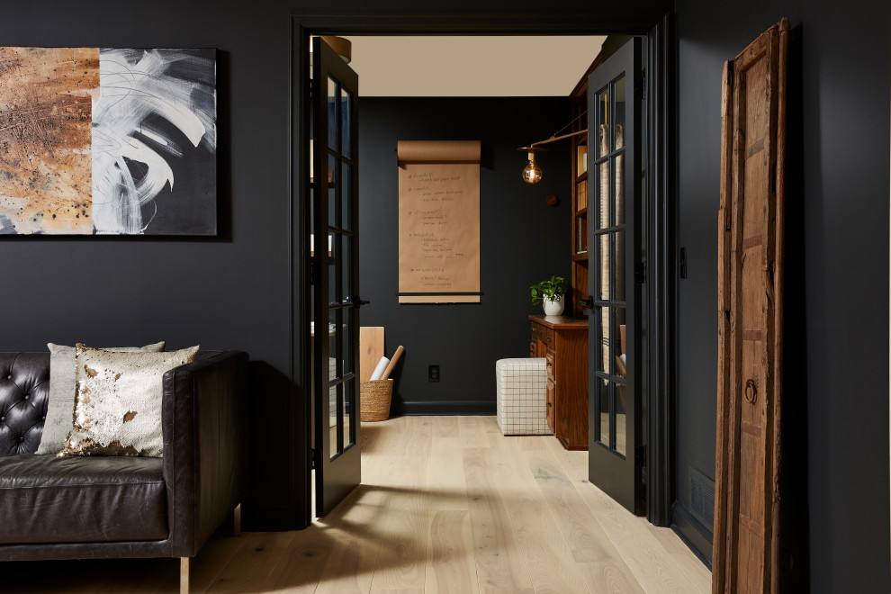 Imagen de estudio moderno de tamaño medio con paredes negras, suelo de madera clara, escritorio independiente y suelo beige