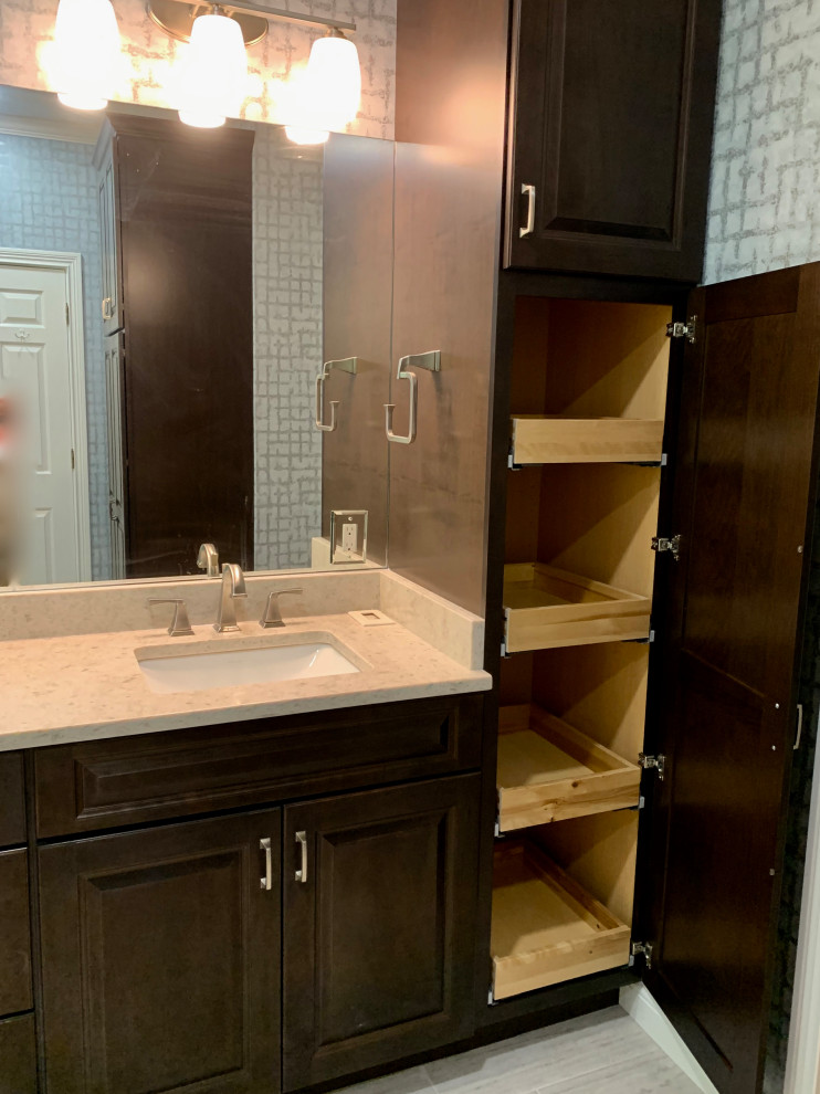 This is an example of a mid-sized transitional master wet room bathroom in Cincinnati with raised-panel cabinets, dark wood cabinets, a drop-in tub, a two-piece toilet, multi-coloured tile, glass tile, multi-coloured walls, porcelain floors, an undermount sink, engineered quartz benchtops, beige floor, beige benchtops, a niche, a double vanity, a built-in vanity and wallpaper.